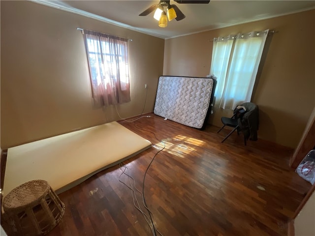 unfurnished bedroom featuring dark wood-type flooring, ceiling fan, and crown molding