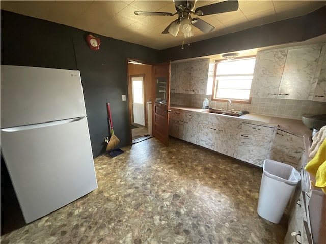 kitchen with ceiling fan, white fridge, backsplash, and sink