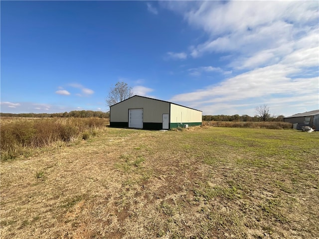 view of outdoor structure featuring a garage, a rural view, and a lawn