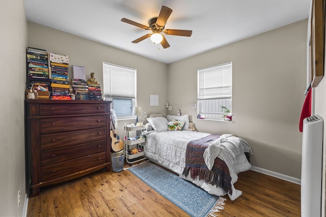 bedroom with hardwood / wood-style floors, ceiling fan, and multiple windows