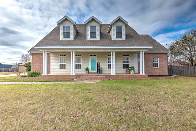 cape cod home featuring a front yard and covered porch