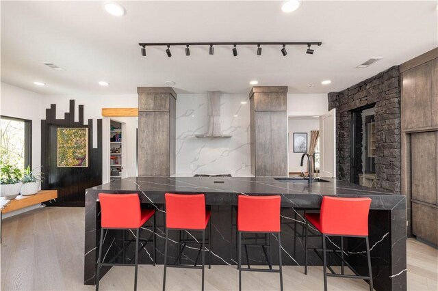 514 N Vinson Ave, Fayetteville, AR 72701 - kitchen featuring wall chimney range hood, a sink, a kitchen breakfast bar, dark countertops, and recessed lighting