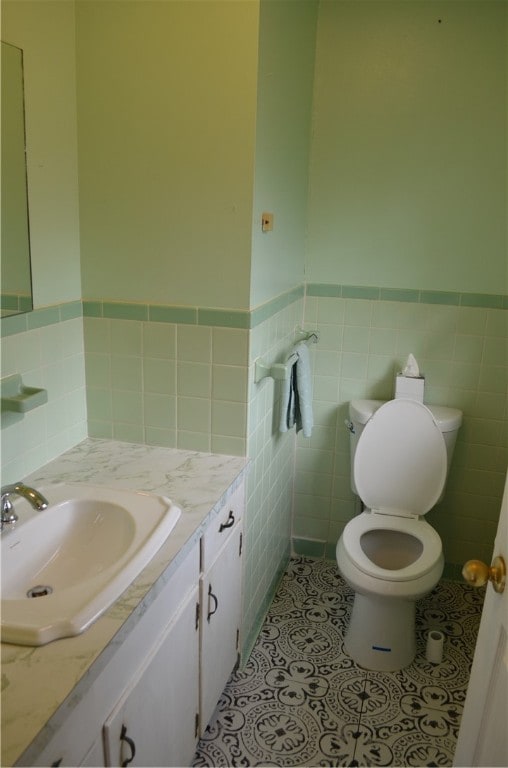 bathroom featuring toilet, vanity, tile patterned floors, and tile walls