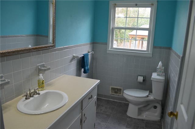 bathroom with vanity, tile patterned flooring, toilet, and tile walls