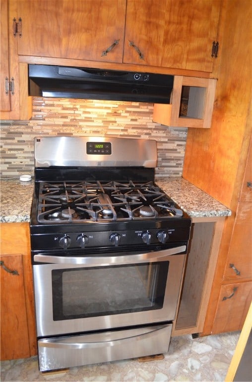 kitchen featuring backsplash, gas range, and light stone counters