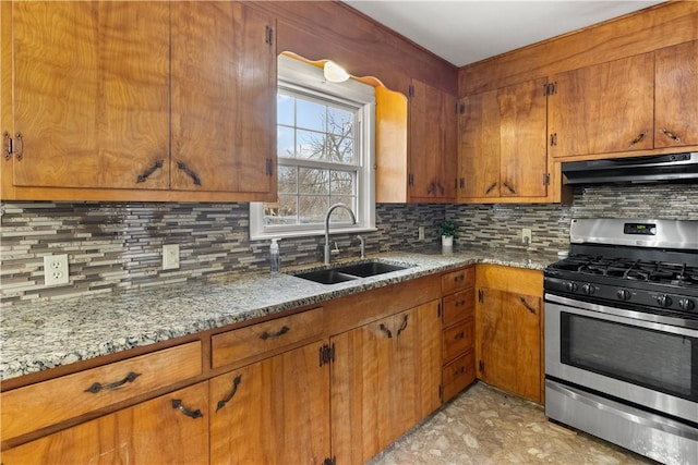 kitchen with under cabinet range hood, a sink, brown cabinets, and stainless steel gas range