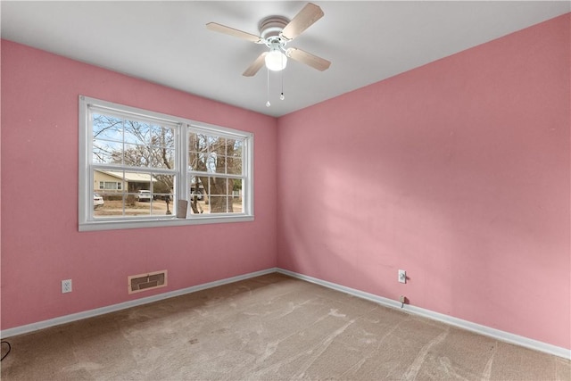 carpeted spare room featuring ceiling fan, baseboards, and visible vents