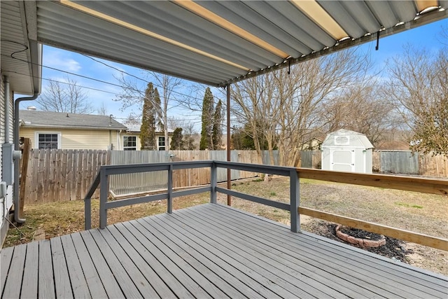 wooden deck with a fenced backyard, an outdoor structure, and a shed