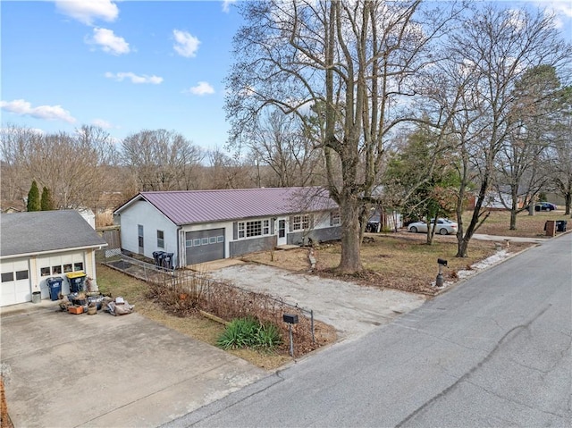 single story home with a standing seam roof, driveway, metal roof, fence, and an attached garage