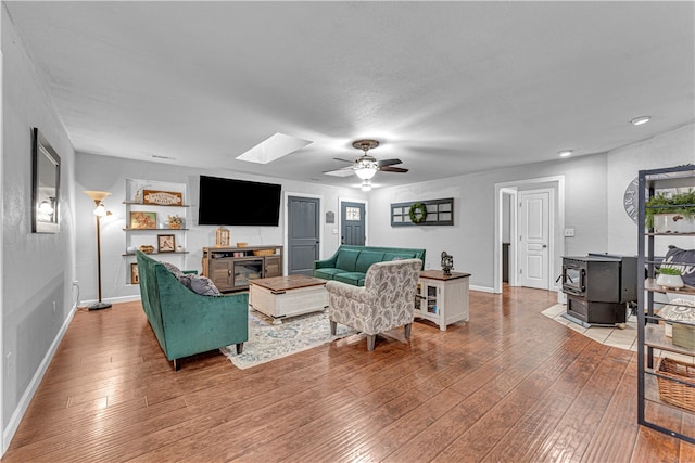 living room with a wood stove, ceiling fan, and hardwood / wood-style flooring