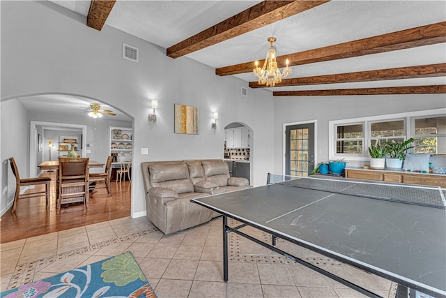 playroom with ceiling fan with notable chandelier, lofted ceiling with beams, built in shelves, a textured ceiling, and light tile patterned flooring