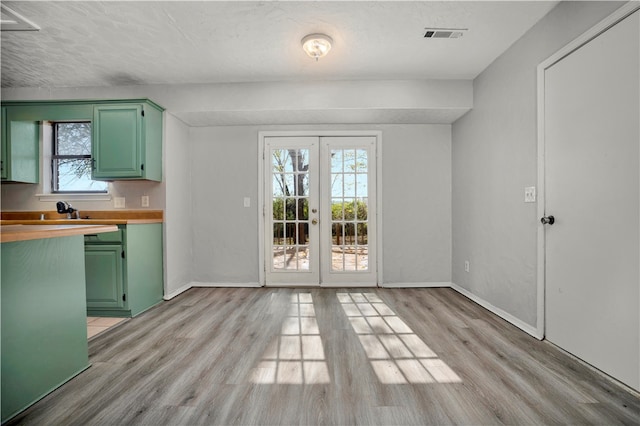 kitchen featuring green cabinets, french doors, light hardwood / wood-style floors, and a textured ceiling