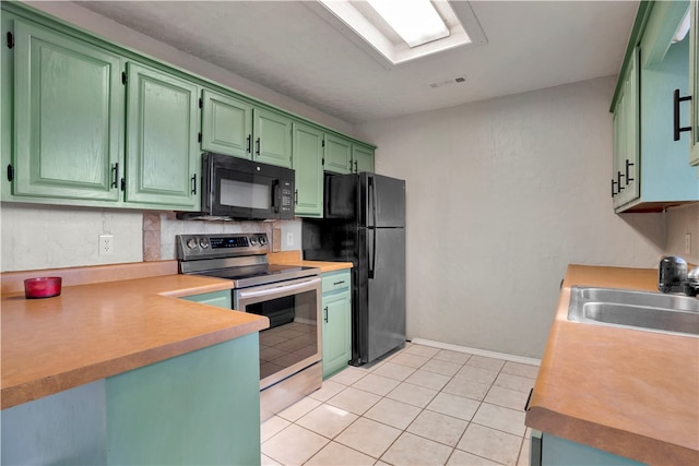 kitchen featuring green cabinets, black appliances, sink, tasteful backsplash, and light tile patterned floors