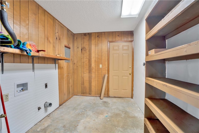 laundry room featuring electric dryer hookup, washer hookup, wooden walls, and a textured ceiling