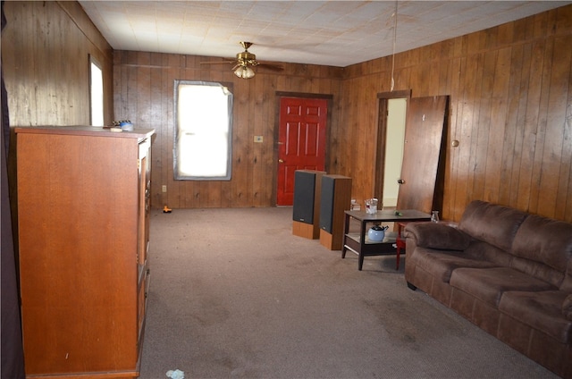 carpeted living room with wood walls and ceiling fan