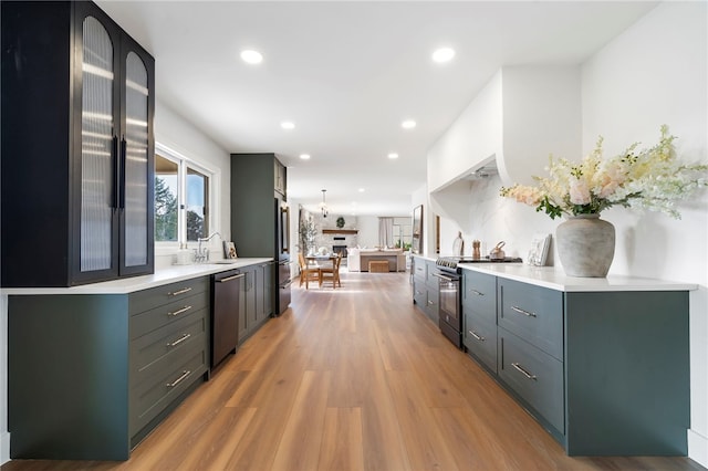 kitchen with appliances with stainless steel finishes, light hardwood / wood-style flooring, pendant lighting, and sink