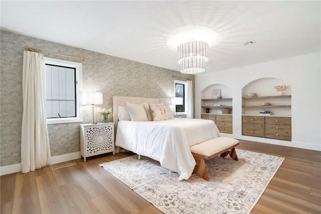 bedroom featuring hardwood / wood-style floors, an inviting chandelier, and multiple windows