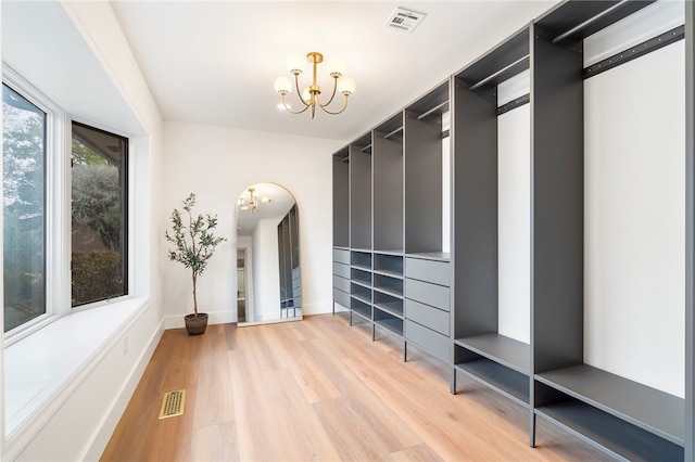 spacious closet featuring hardwood / wood-style flooring and an inviting chandelier