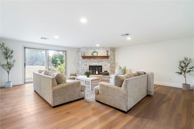 living room featuring a stone fireplace and hardwood / wood-style flooring