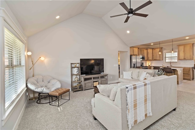 living room with ceiling fan, high vaulted ceiling, and light carpet