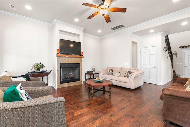 living room featuring ceiling fan, dark hardwood / wood-style flooring, ornamental molding, and a fireplace