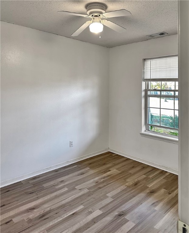 empty room featuring light hardwood / wood-style floors, ceiling fan, and a textured ceiling