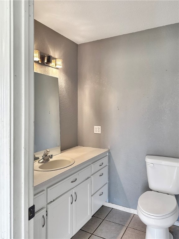 bathroom with toilet, vanity, and tile patterned floors