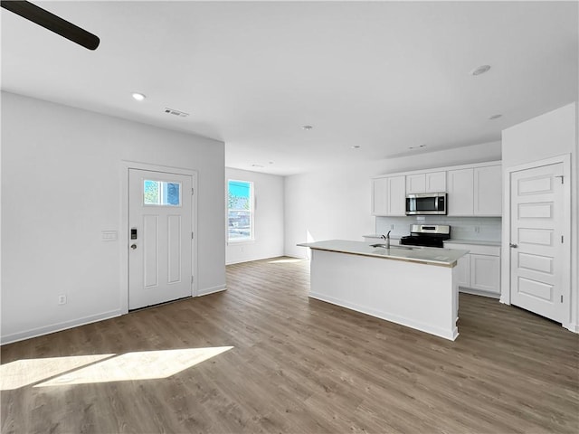 kitchen with visible vents, open floor plan, wood finished floors, appliances with stainless steel finishes, and white cabinets