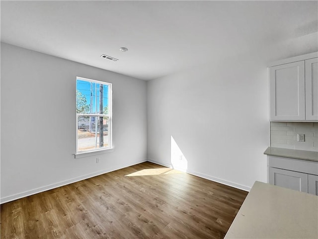 unfurnished dining area with visible vents, baseboards, and wood finished floors