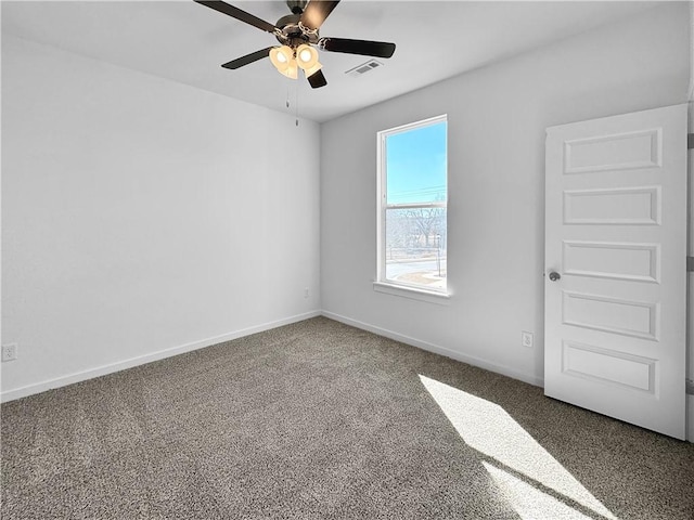 carpeted empty room featuring visible vents, a ceiling fan, and baseboards