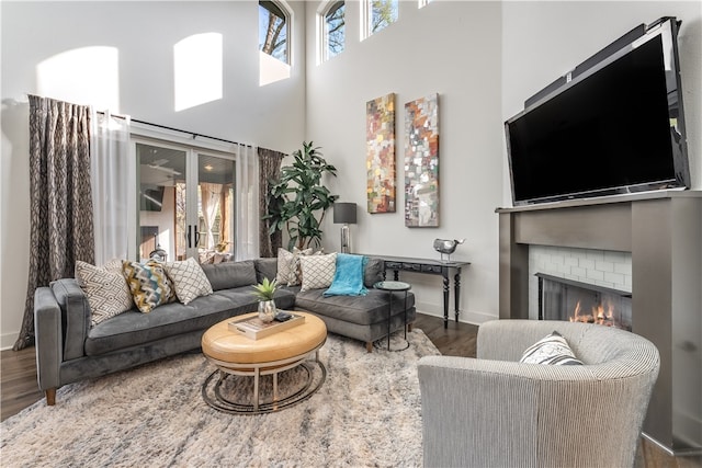 living room with dark hardwood / wood-style floors, a fireplace, and a high ceiling