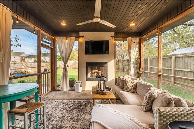 sunroom / solarium featuring ceiling fan, a healthy amount of sunlight, wood ceiling, and an outdoor fireplace