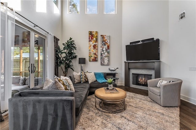 living room with a towering ceiling, dark wood-type flooring, and a wealth of natural light