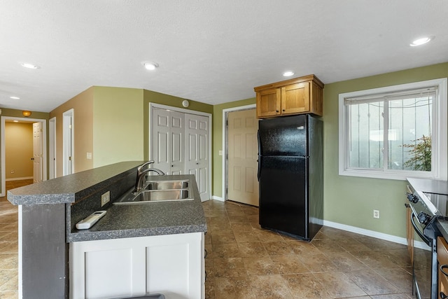 kitchen with electric range, black refrigerator, and sink