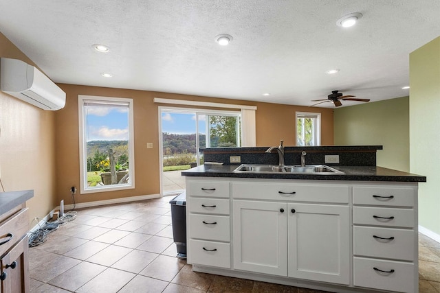 kitchen featuring a wall mounted air conditioner, sink, ceiling fan, a textured ceiling, and white cabinetry