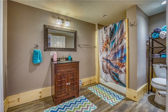 bathroom with toilet, vanity, hardwood / wood-style flooring, and curtained shower