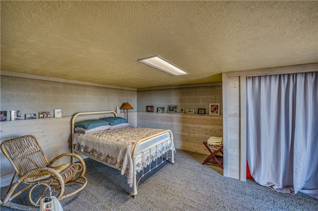 carpeted bedroom with a textured ceiling and wooden walls