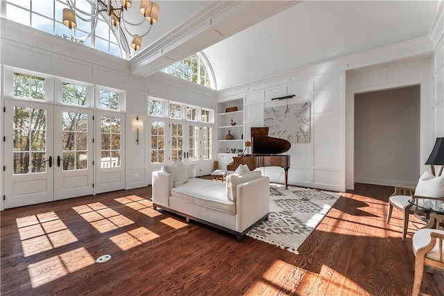 living room with built in shelves, french doors, crown molding, a notable chandelier, and dark wood-type flooring