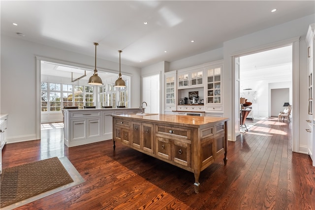 kitchen featuring hanging light fixtures, an island with sink, and white cabinets