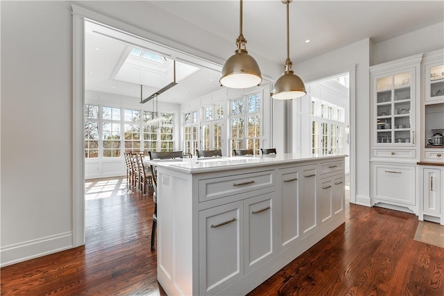 10760 Sugar Creek Rd, Bentonville, AR 72712 - kitchen featuring a skylight, dark wood-style flooring, white cabinets, a kitchen island, and pendant lighting