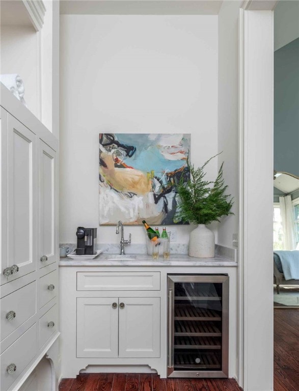 bar with dark wood-type flooring, beverage cooler, sink, and white cabinets