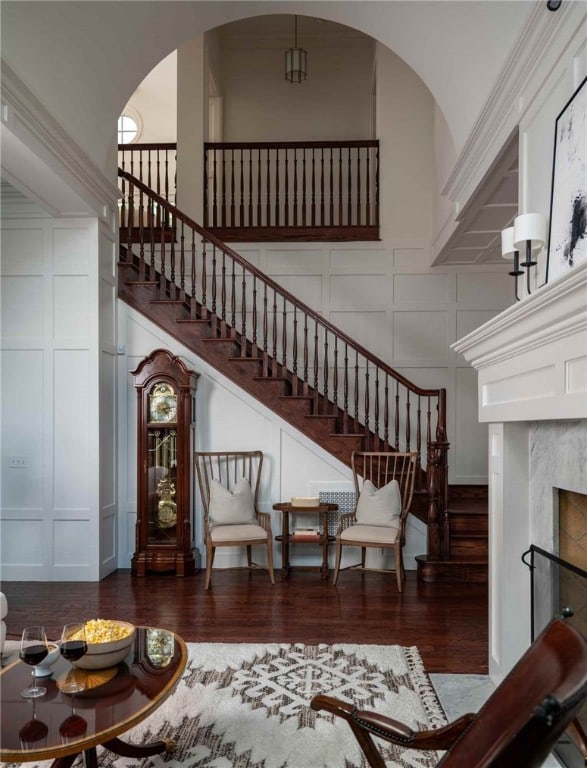 stairs with a towering ceiling, a premium fireplace, and hardwood / wood-style flooring