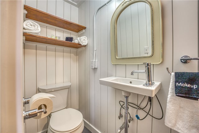 bathroom featuring toilet and wood walls