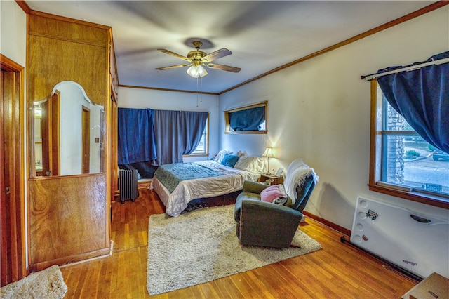 bedroom featuring light hardwood / wood-style floors, radiator heating unit, multiple windows, and ceiling fan