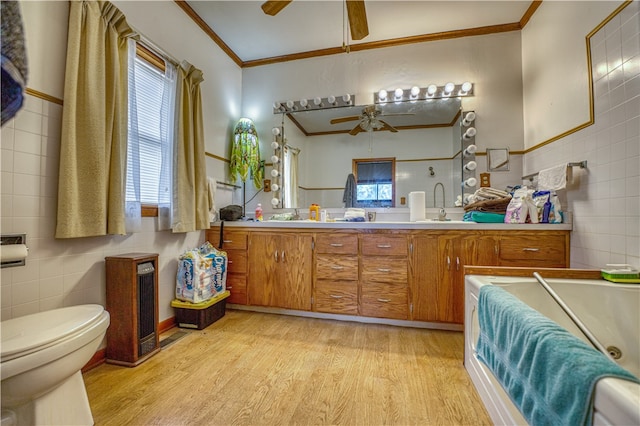 bathroom featuring wood-type flooring, tile walls, vanity, ceiling fan, and crown molding