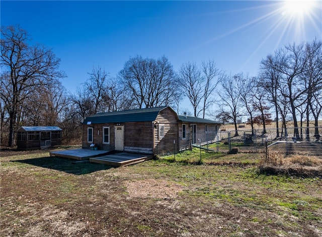 rear view of property featuring an outdoor structure and a wooden deck