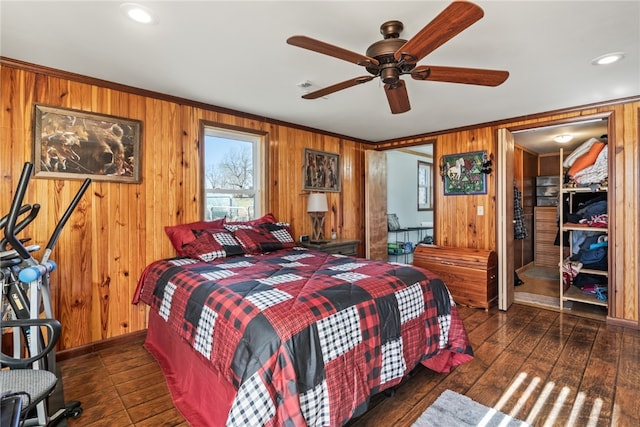 bedroom with ceiling fan, dark hardwood / wood-style flooring, wood walls, and ornamental molding