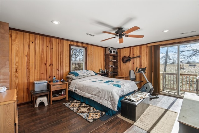 bedroom with wood walls, ceiling fan, dark hardwood / wood-style floors, and multiple windows