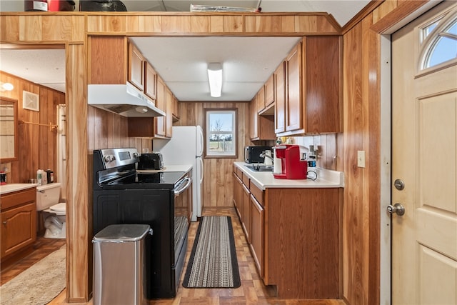 kitchen featuring electric range, light parquet floors, and wooden walls