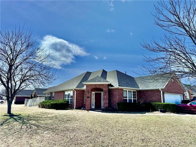 view of front of home with a front yard, brick siding, fence, and an attached garage